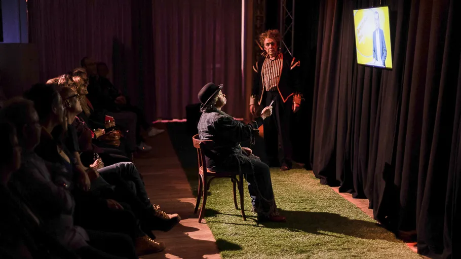 Man pointing at screen, audience watching.