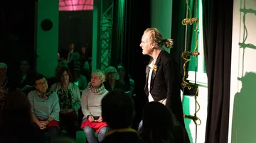 Performer on stage, audience watching intently.