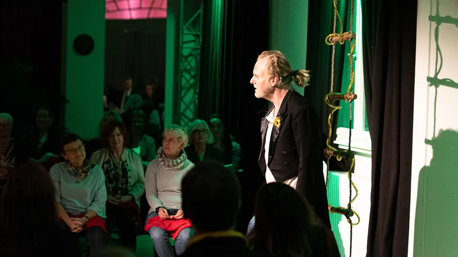 Performer on stage, audience watching intently.