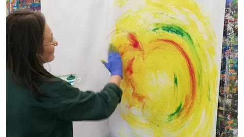 Person painting colorful swirls on canvas