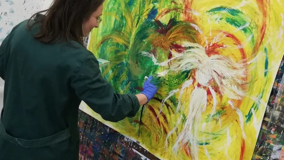 Artist painting colorful abstract piece in studio.