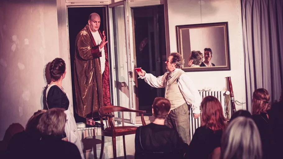 Actors perform in a living room setting.