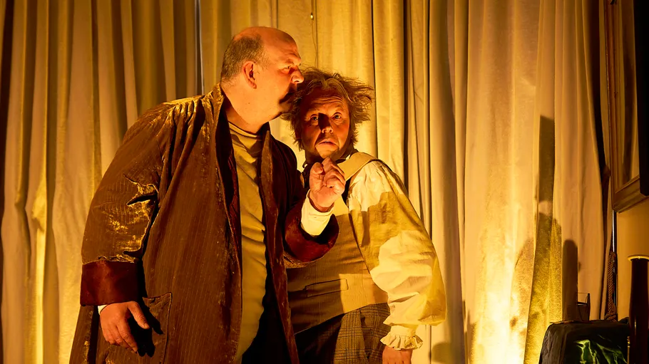 Zwei Schauspieler in historischen Kostümen, gedämpftes Licht.