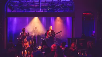 Bühnenauftritt mit Musikern und Publikum.