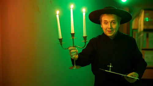 Person holding candelabra in dimly lit room.
