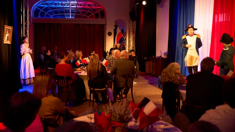 Actors perform Napoleon-themed play in decorated room.