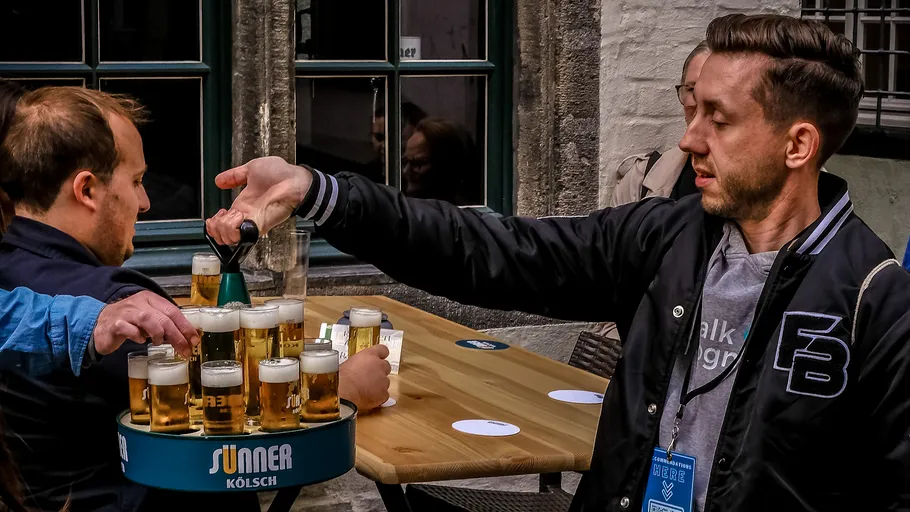 Mann serviert Fassbier an einem Außentisch.