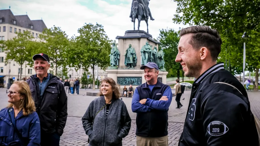 Group of people smiling near a statue in square.