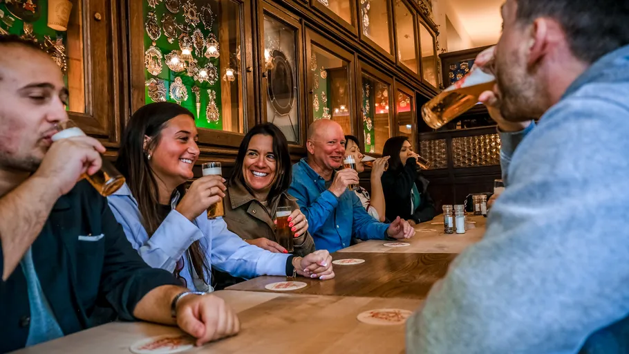 People drinking beer at wooden table indoors.