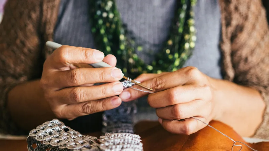 Hands crocheting with metal ring material.