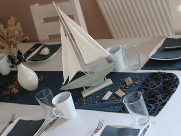 Sailing ship on a covered table with decoration and glasses.