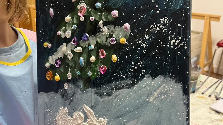 Kind hält glitzerndes Weihnachtsbild.