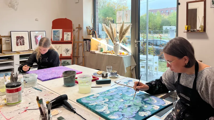 Two people painting in a bright studio.