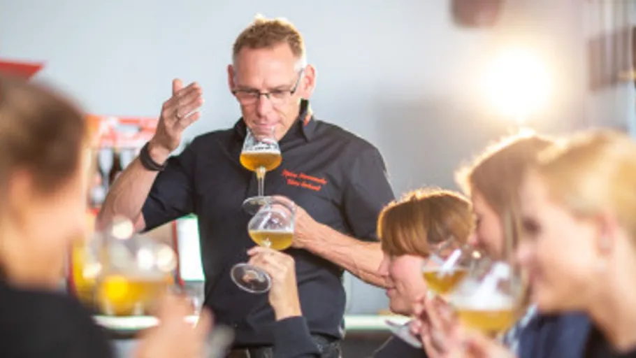 Man tasting beer while others observe.