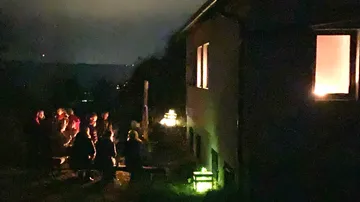 People gathering outdoors at night near building.