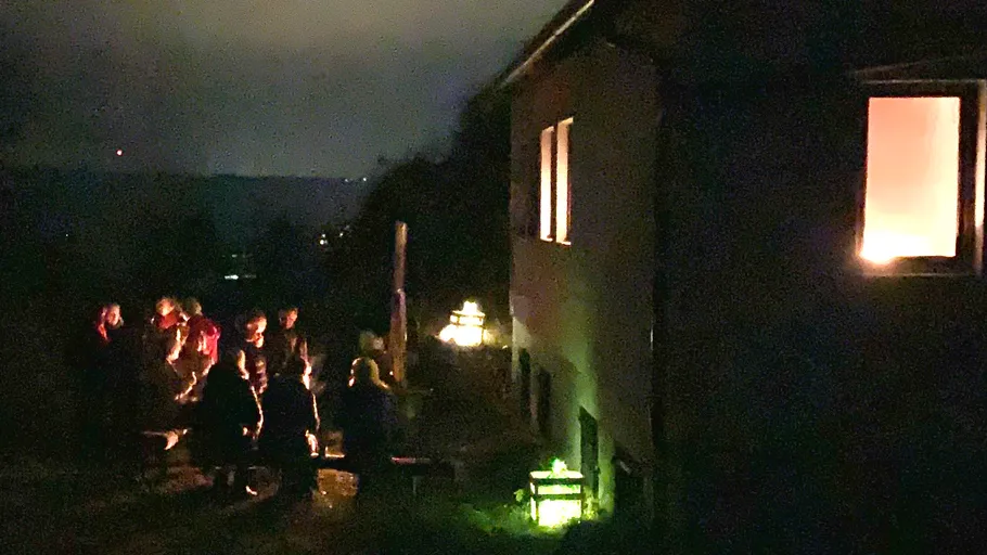Menschen versammeln sich nachts draußen am Gebäude.