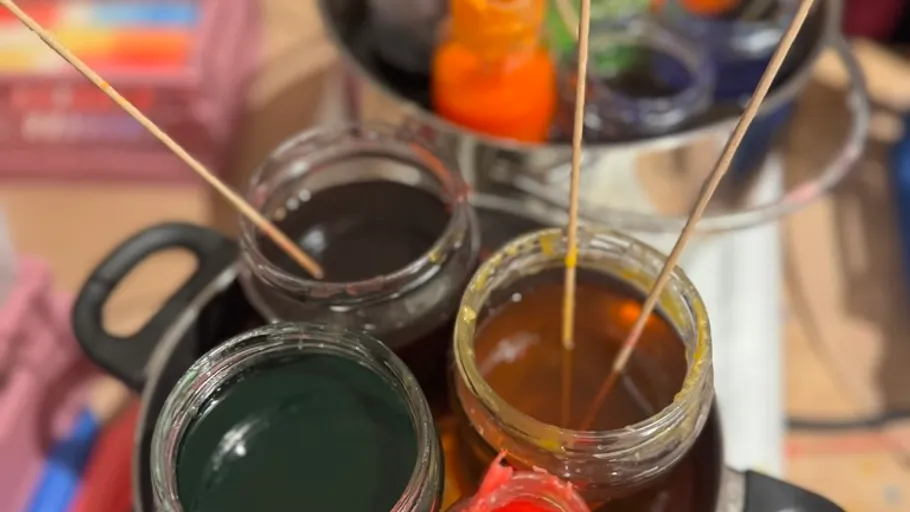 Jars of paint with sticks in studio.