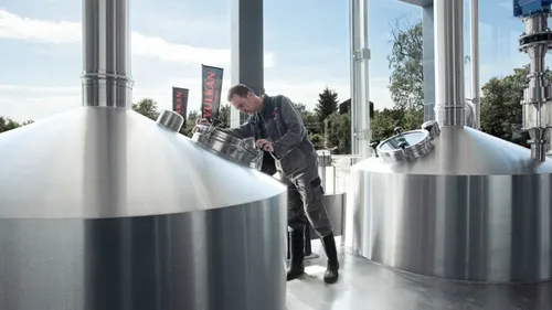 Arbeiter inspiziert große Edelstahltanks, Brauerei.