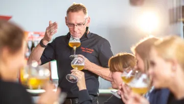 Man tasting beer in group setting.