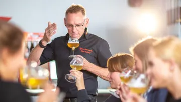 Mann probiert Bier mit mehreren Personen in der Nähe.
