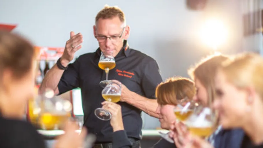 Mann probiert Bier mit mehreren Personen in der Nähe.