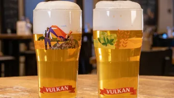 Two glasses of beer on wooden table.