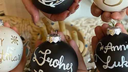 Hands holding decorated Christmas ornaments indoors.