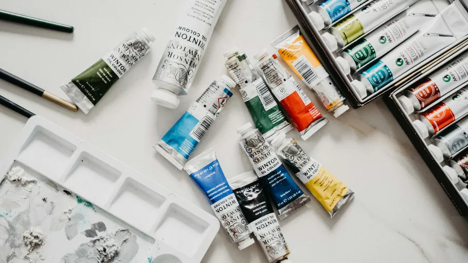 Paint tubes and brushes on a white table.