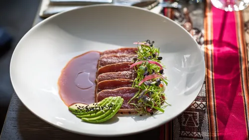 Seared tuna with avocado and greens on plate.