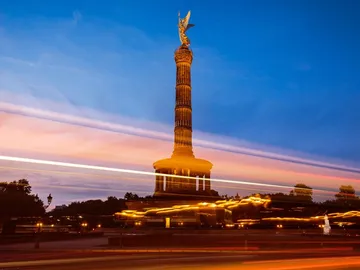 Column with angel, glowing at sunset, surrounded by movement.