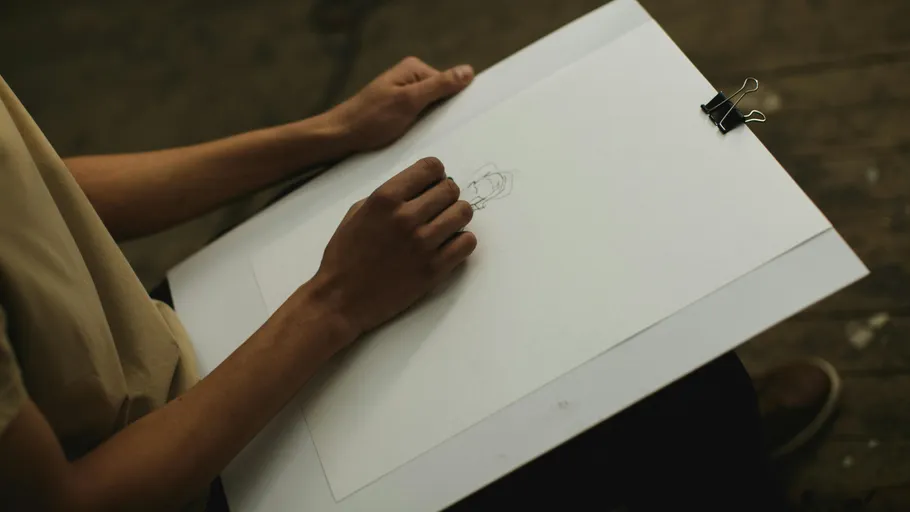 Person drawing on large paper, sitting indoors.