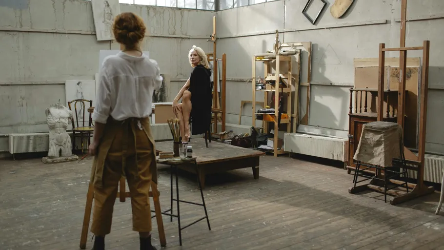 Artist painting a model in a studio.