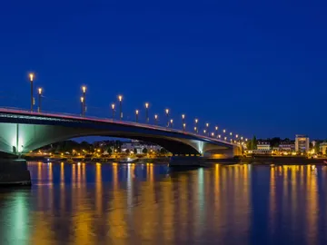 Bright bridge over reflecting water at night.