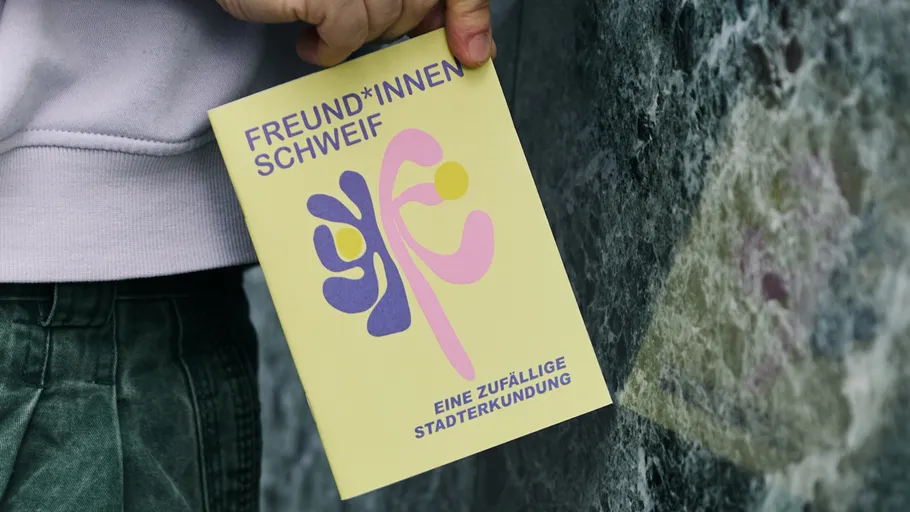 Hand holding booklet near grey wall.