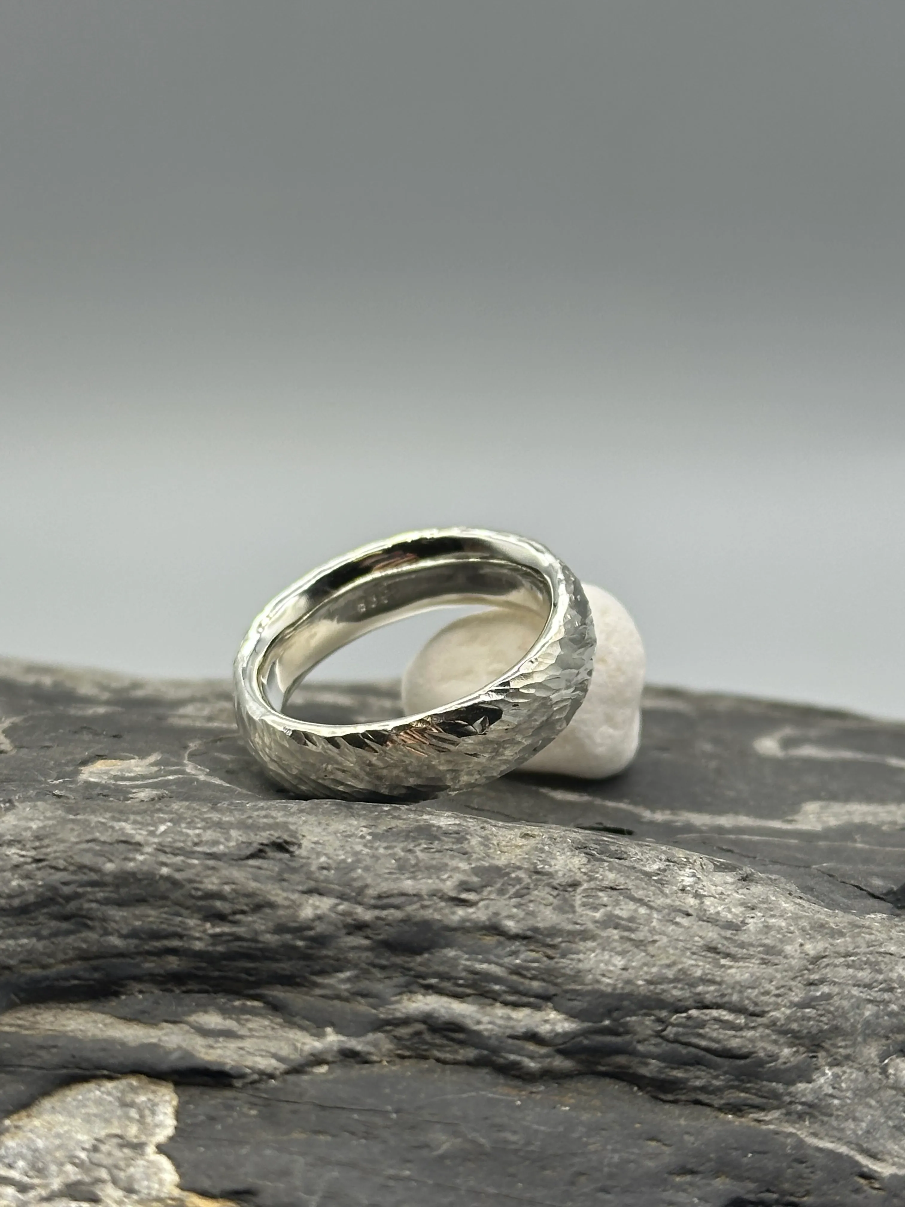 Silberring auf strukturiertem Steinoberfläche.