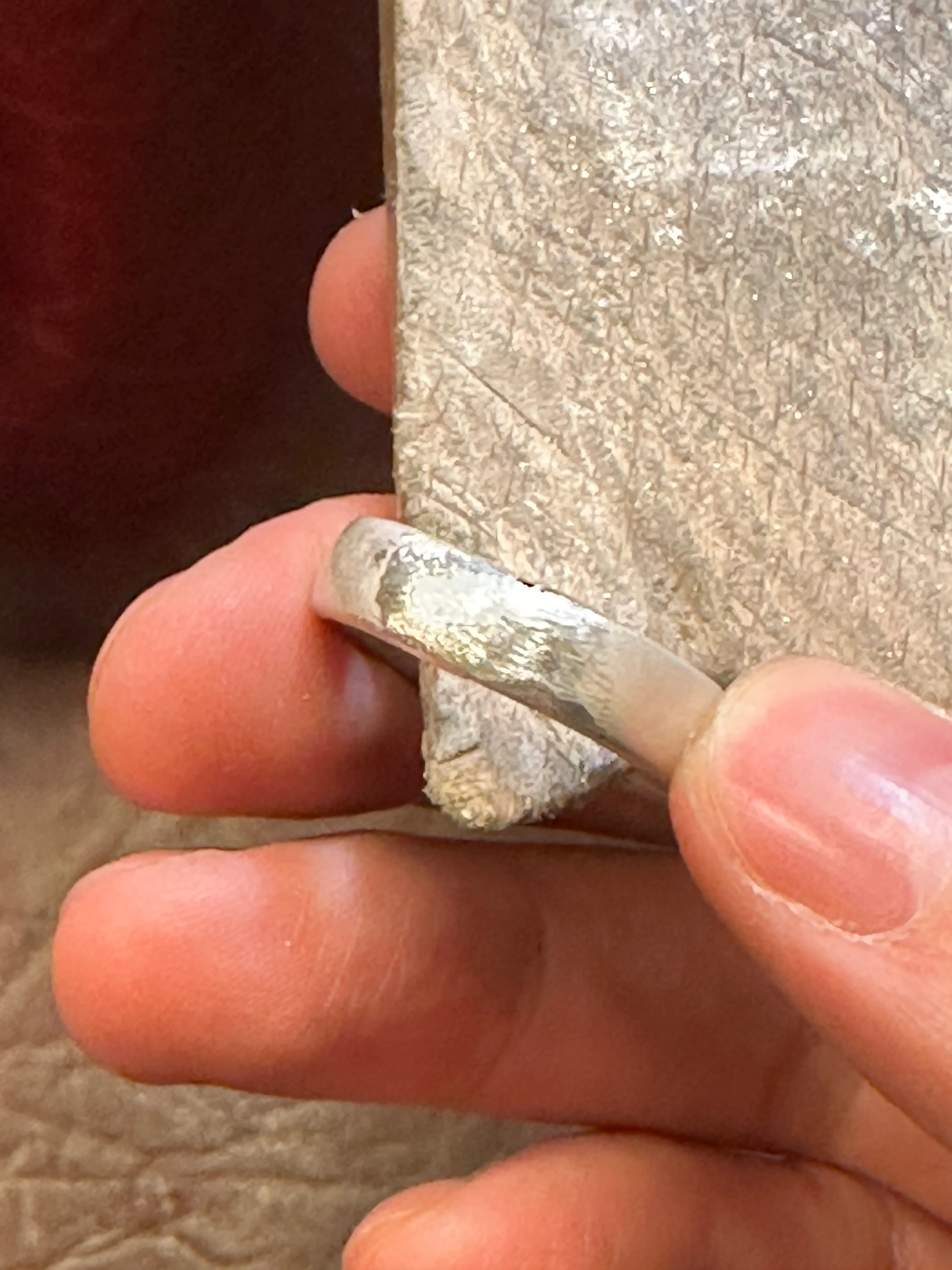 Hand hält roh geschnittenen Ring und Stein.