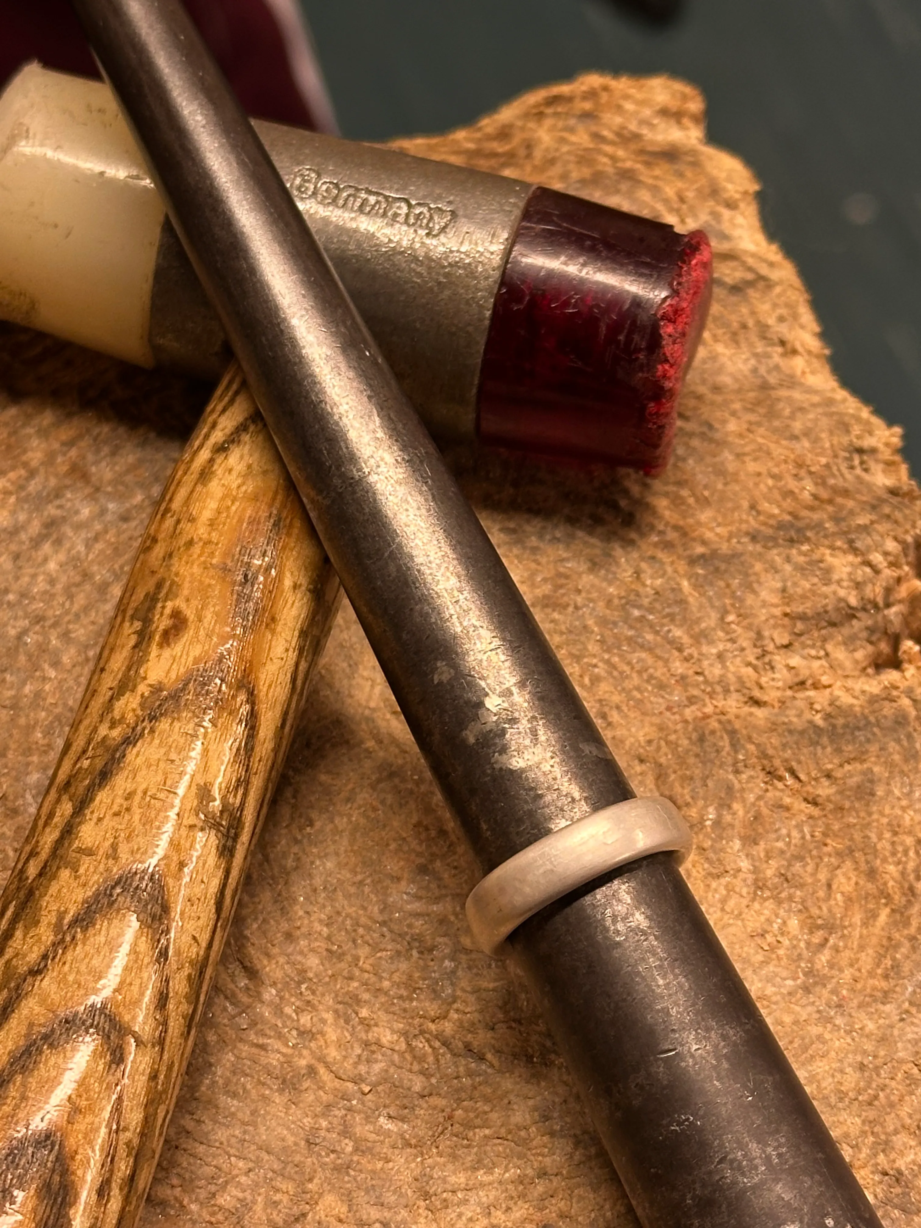 Hammer und Ring auf Metallstab, Holzoberfläche.