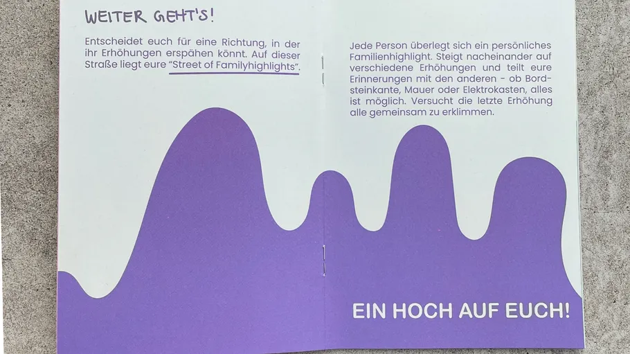 Booklet with purple wave design on concrete.