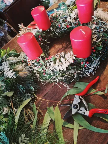 Rote Kerzen auf dekorativem Kranz, Holztisch.