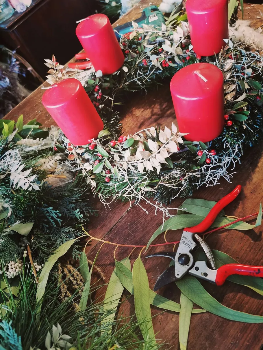 Red candles on decorative wreath, wooden table.