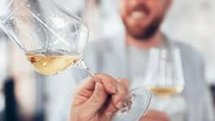 Person holding a tilted wine glass, smiling background.
