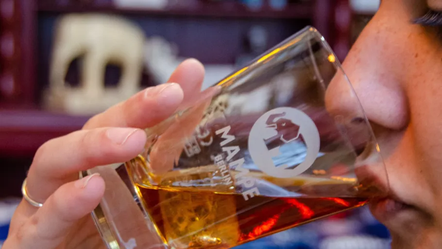 Person drinking from Mampe glass indoors.