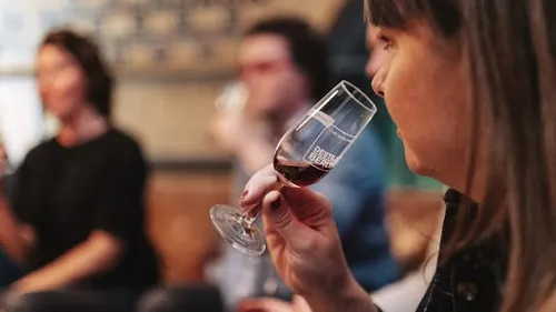 Frau kostet Rotwein in geselliger Runde.