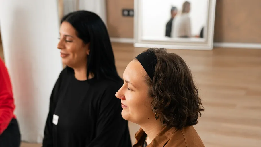 Two women sitting and smiling indoors.