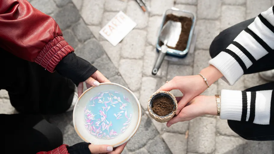Hands holding bowl and soil on pavement.
