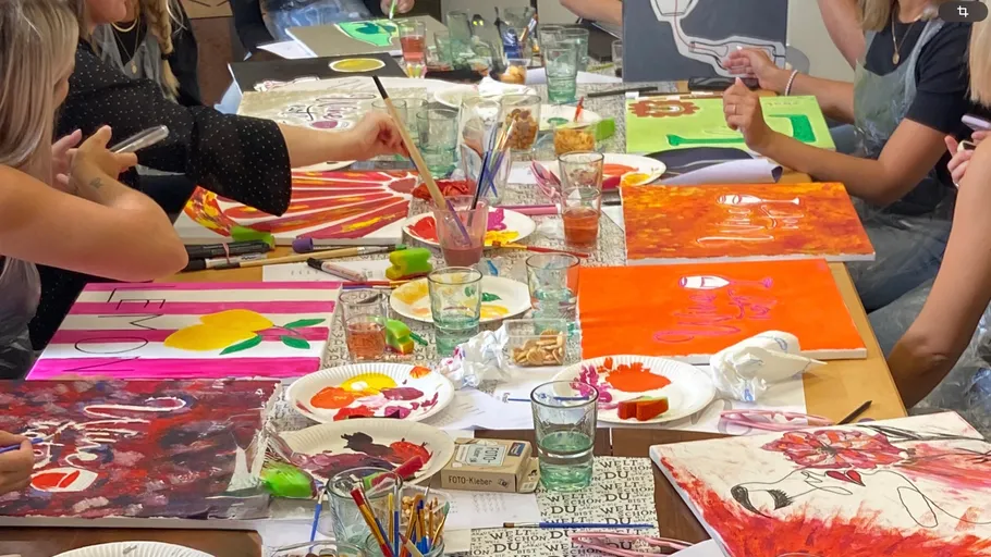 People painting on tables in a classroom.