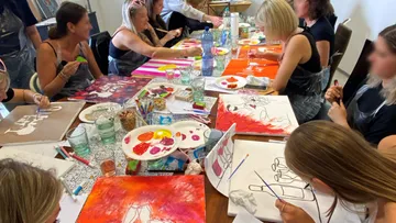 Personen malen gemeinsam an einem Workshop-Tisch.