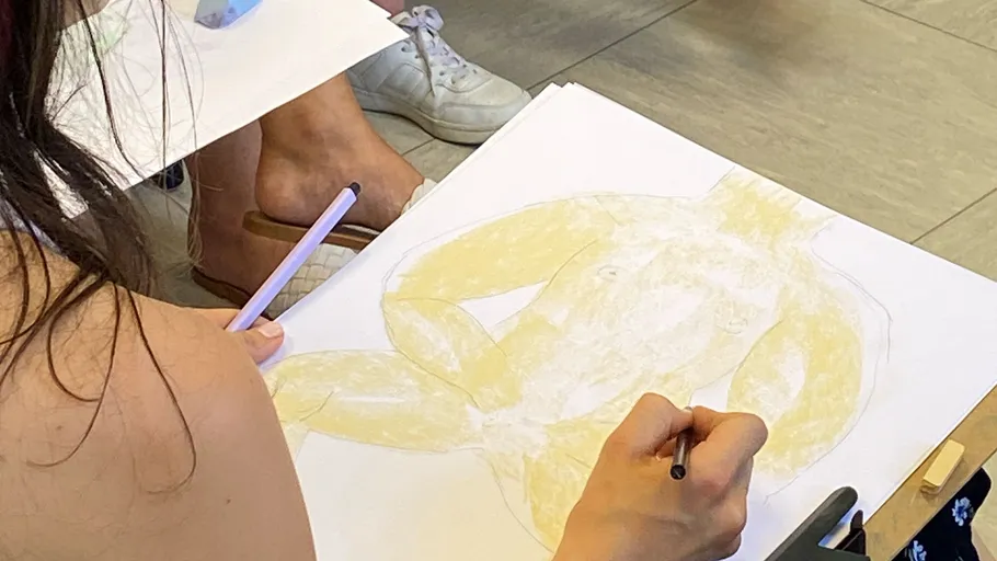 Person zeichnet eine Figur im Kunstkurs.
