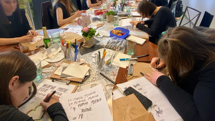 People practicing calligraphy around a table.