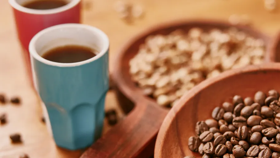 Coffee beans and cups on wooden table.